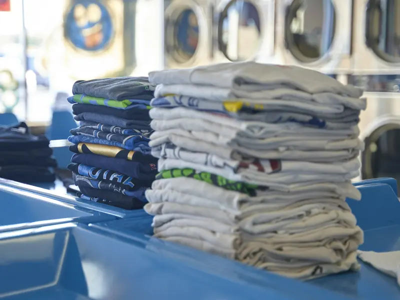 Pilas de camisetas dobladas listas para entregar: lavado al peso