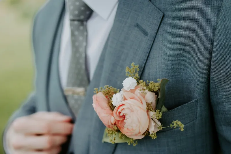 Detalle de un terno azul grisáceo con corbata de lunares y flores en el bolsillo: limpieza de ternos y corbatas